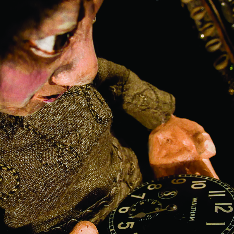 Close-up of puppet staring at a the hands of a pocket watch