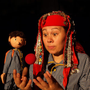 A fortune-telling genie, and boy (puppet) look expectantly at a floating red ball